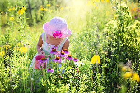 women wearing white maxi dress and pink hat in Garden during day time thumbnail