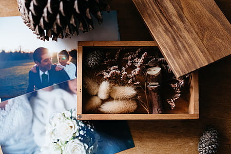 flat lay photography of photos and wilted pine cones and flowers in wooden box thumbnail
