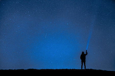 person silhouette holding flashlight on blue sky thumbnail