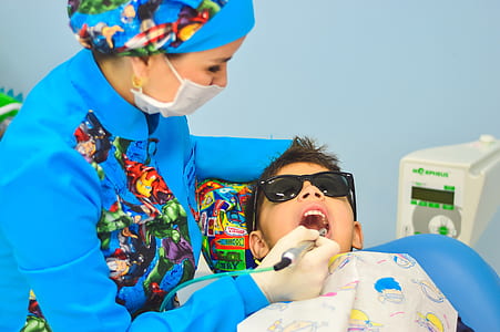 dentist checking boy's teeth wearingblack sunglasses thumbnail