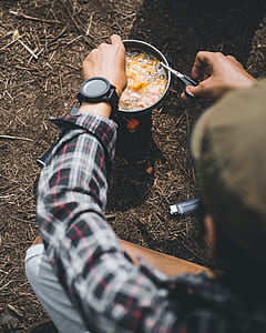 person cooking on camping stove outdoor during daytime thumbnail