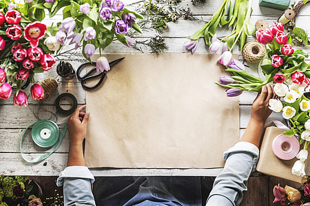 person sitting beside table with paper and tulip flowers thumbnail