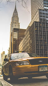 parked yellow Ford Crown Victoria with Chrysler Building background during daytime thumbnail