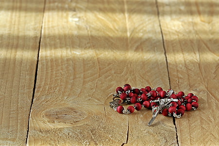 red and silver rosary on wooden surface thumbnail