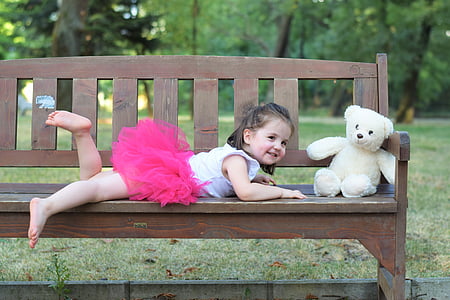 baby wears pink tutu skirt near white bear on brown wooden bench thumbnail
