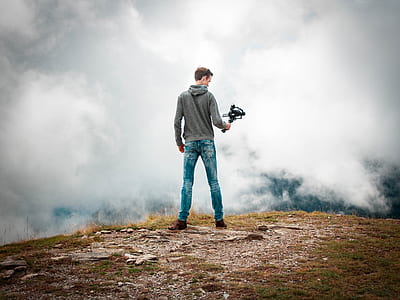 man holding camera stabilizer facing on cumulus clouds thumbnail
