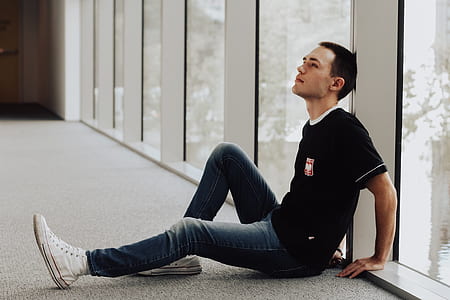 man sitting on floor while leaning on wall thumbnail