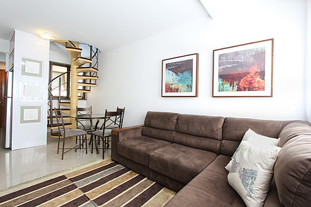 two nature paintings hanged on white wall above brown sectional couch thumbnail