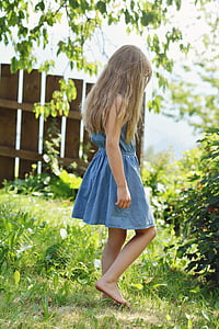 girl in blue chambray dress stands on green grass field at daytime thumbnail