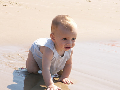baby wearing white shirt crawling on grey sand during day time thumbnail