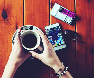 person holding white ceramic coffee cup on brown surface thumbnail