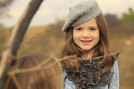 selective focus photography of smiling girl wearing gray and blue long-sleeved dress thumbnail