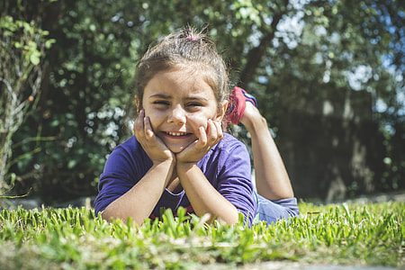 girl lying on green grass with hands on her cheeks thumbnail