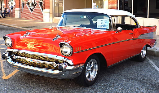 close-up photography of red Chevrolet Bel Air coupe on concrete road at daytime thumbnail