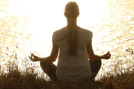 woman meditating near body of water thumbnail