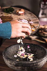 Person Pouring Sliced Spices from a Chopping Board to Black Bowl thumbnail