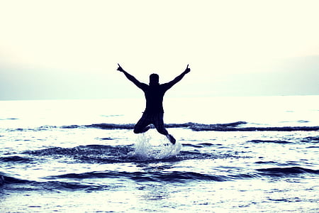photo of man jump on sea during daytime thumbnail