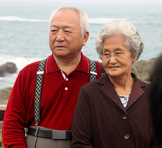 woman in brown coat in front of man in red polo shirt near body of water thumbnail
