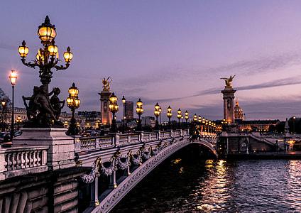 lighted street lamps on bridge over body of water thumbnail