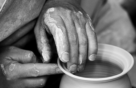 grayscale photo of person's hands molding pot thumbnail