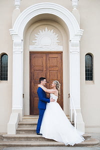 newly wed bride and groom looking at each other in front of house thumbnail