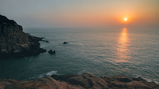 calm body of water and brown rock formation during golden hour thumbnail