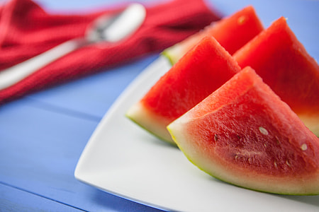 Fresh slices of water melon fruit sit on a blue tabletop, image captured with a Canon DSLR thumbnail