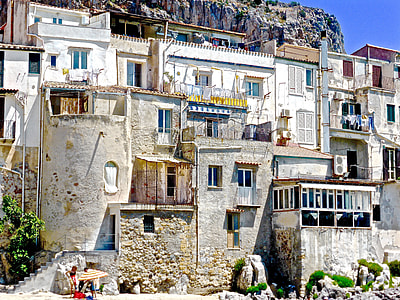 white and grey concrete buildings beside rock hill under blue sky thumbnail