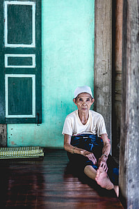 person wearing white t-shirt sitting on floor beside green wall thumbnail