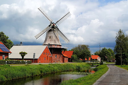 red and white house beside windmill near road during daytime thumbnail