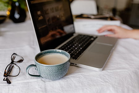 A woman works at a desk with a laptop and a cup of coffee thumbnail
