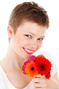 woman holding pink and orange gerbera flowers thumbnail