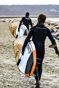 two men carrying brown surfboard walking on seashore thumbnail