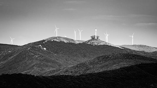 grayscale photography of windmill on mountains thumbnail