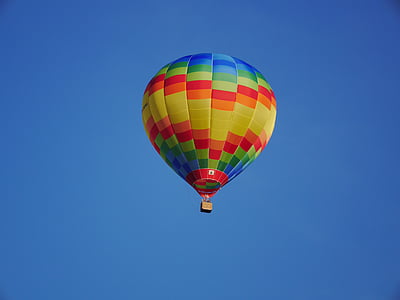 yellow, red, and blue hot air balloon soaring in sky thumbnail