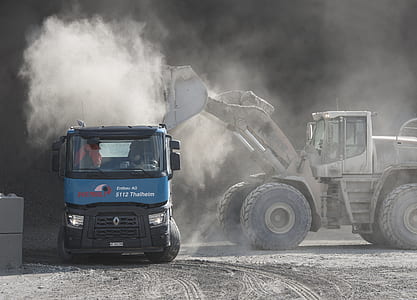 grey front loader loading sand on blue dump truck during daytime thumbnail