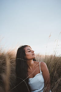 woman standing on grass while closing her eyes during daytime thumbnail