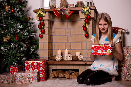 girl holding a Christmas gift near fireplace mantel thumbnail