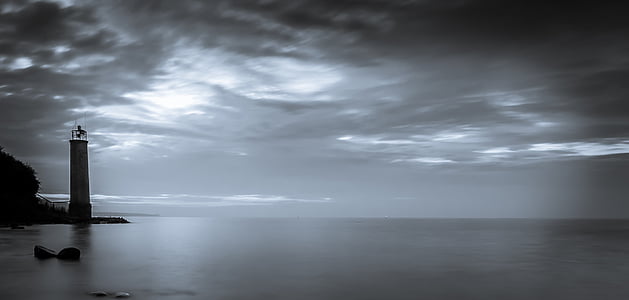 greyscale photography of lighthouse near ocean thumbnail