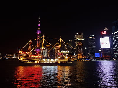 illuminated ship sailing near city thumbnail