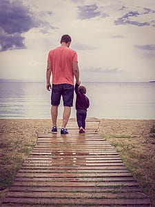 father and child walking on wooden dock thumbnail