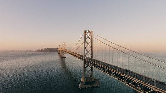 body of water under brown bridge under white sky thumbnail