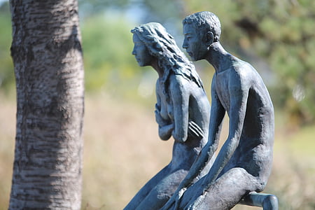 man and woman sitting on rail statues thumbnail