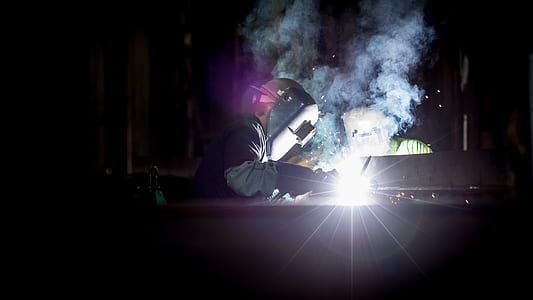 person wearing gray welding mask fabricating steel frame thumbnail