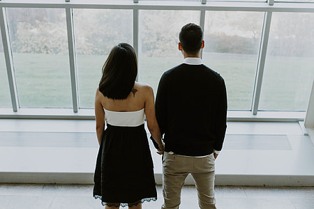 A young couple standing by large windows thumbnail