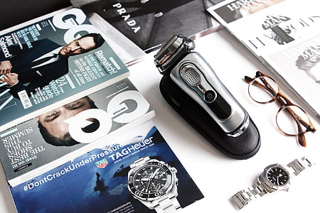 round black analog watch with silver-colored linked strap beside magazine on table thumbnail