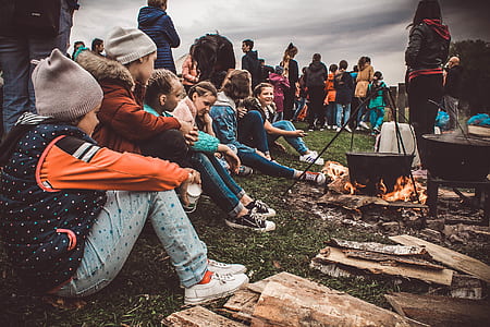 group of people standing and seating beside bonfire thumbnail
