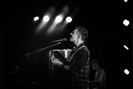 man in front of microphone on grayscale photography thumbnail