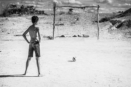 man standing in front of goal net beside soccer ball thumbnail