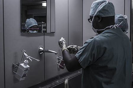 man wearing grey shirt washing his hand near grey stainless steel faucet and mirror inside room thumbnail
